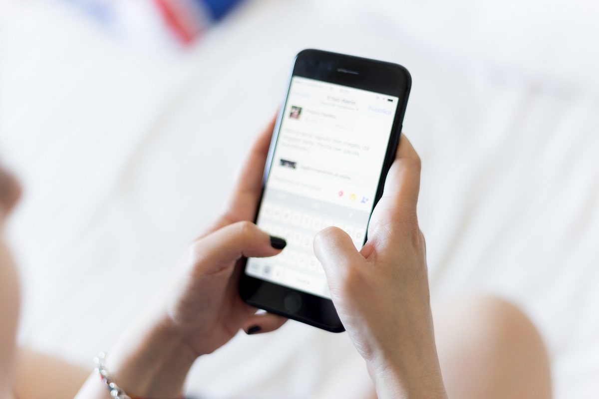 Minimalismus Apps: Frau mit schwarz lackierten Fingelnägeln tippt auf dem Smartphone